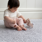 Baby girl playing with baby toy on non toxic kids play mat with grey leopard print pattern