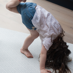 Little girl practices yoga on extra large yoga mat with modern chevron design