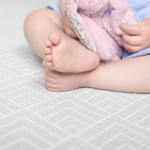 Baby sits unaided with the protection of a padded play mat