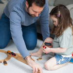 Father and daughter playtime with wooden brio trains on a stylish light grey play rug