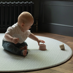 Baby plays on jumbo round play mat by totter and tumble with grey chevron design