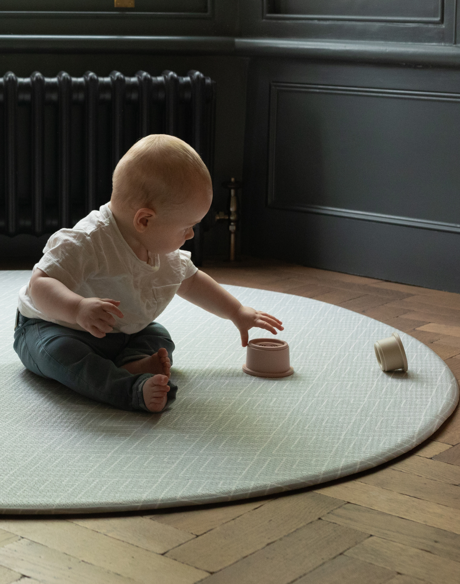 Baby plays on jumbo round play mat by totter and tumble with grey chevron design