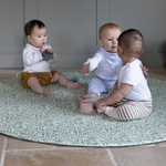 Three babies playing together on round Totter and Tumble play mat with a textured memory foam surface to support little ones as they play featuring the iconic Willow Boughs design from the William Morris archives released for a new generation